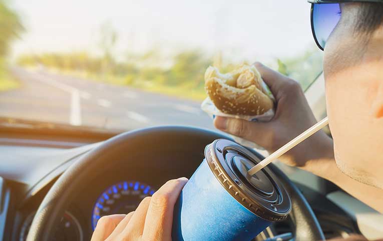 You shouldn't eat and drink while you're driving - rather stop for a break if you're hungry or thirsty.