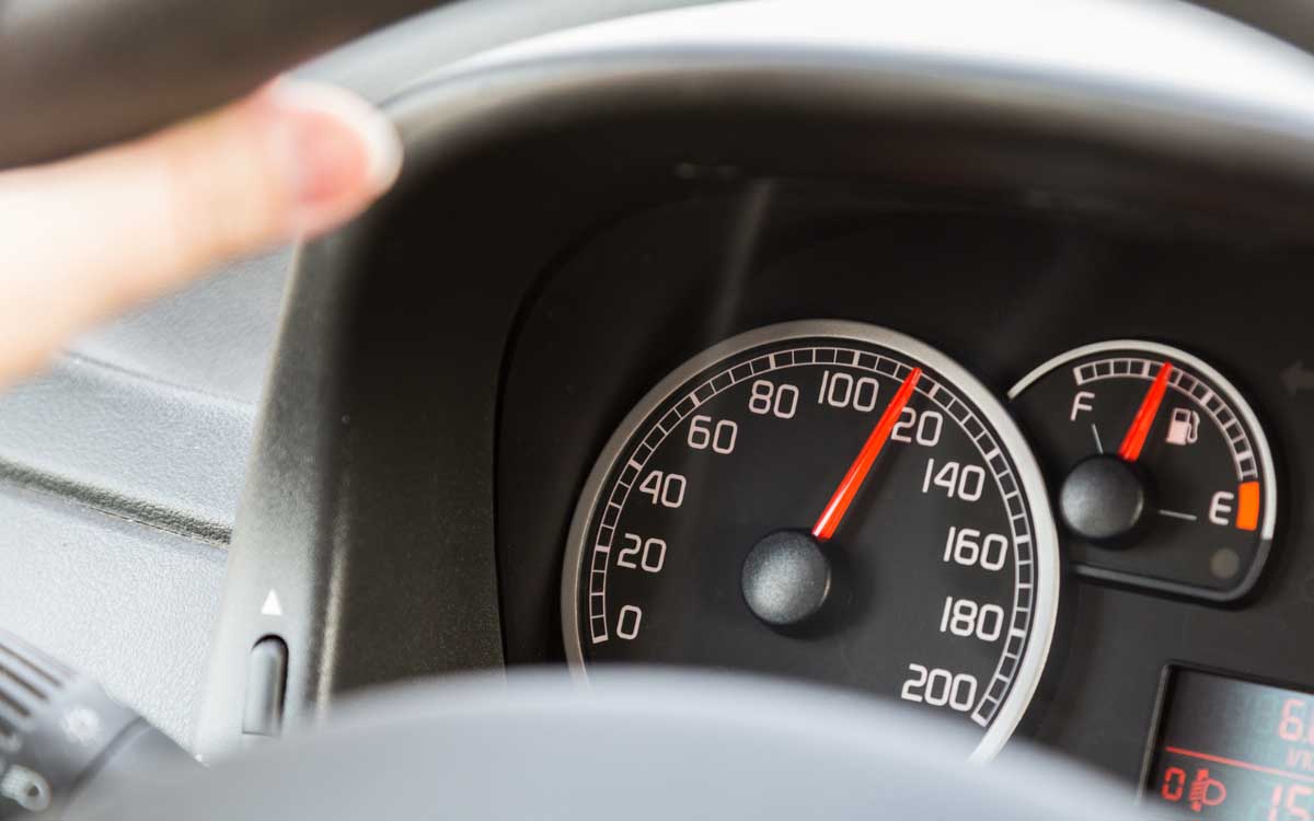 A close-up view of a car's speedometer, with the needle indicating approximately 100 kilometers per hour. The fuel gauge on the right also shows a full tank.